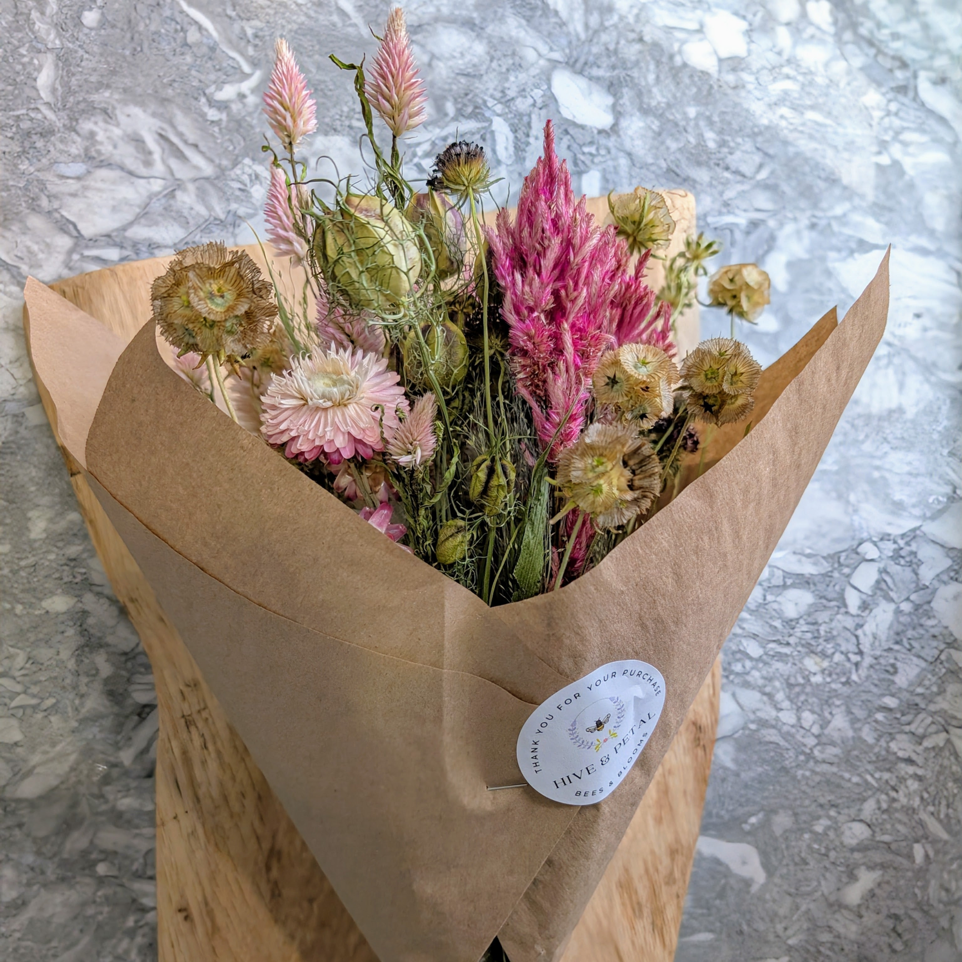 Bouquet of flowers wrapped in brown paper with a label on a gray surface