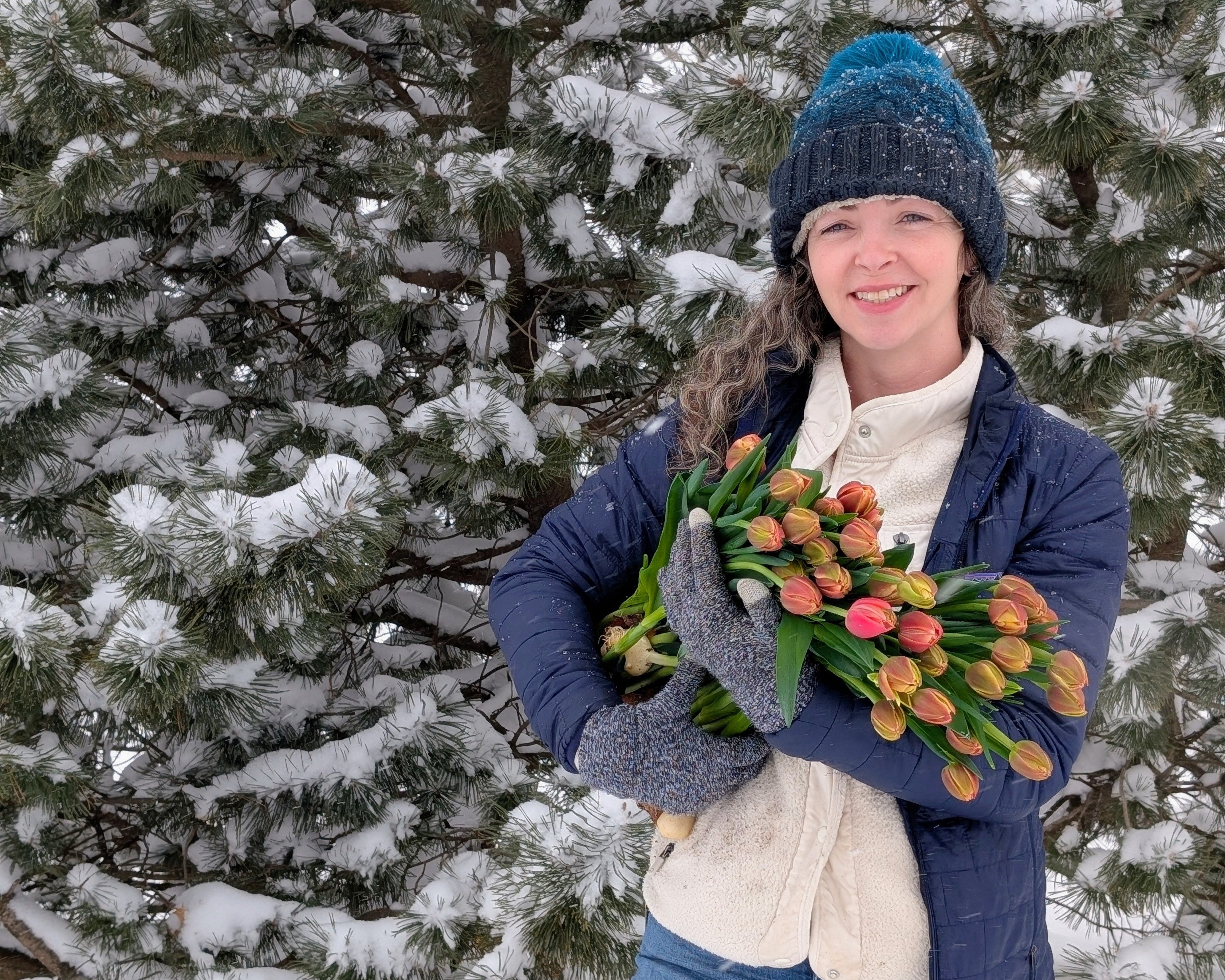 Person holding flowers in a snowy landscape with trees
