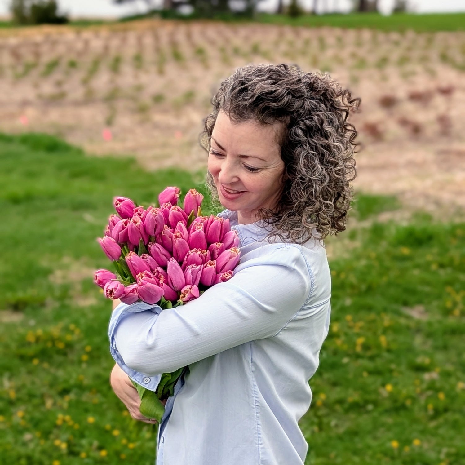 Woman holding a bouquet of pink tulips in an outdoor setting