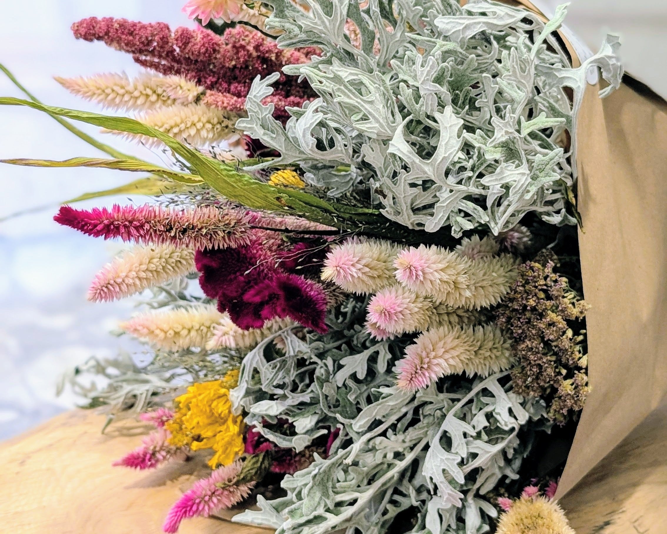 Bouquet of dried flowers with greenery on a wooden surface