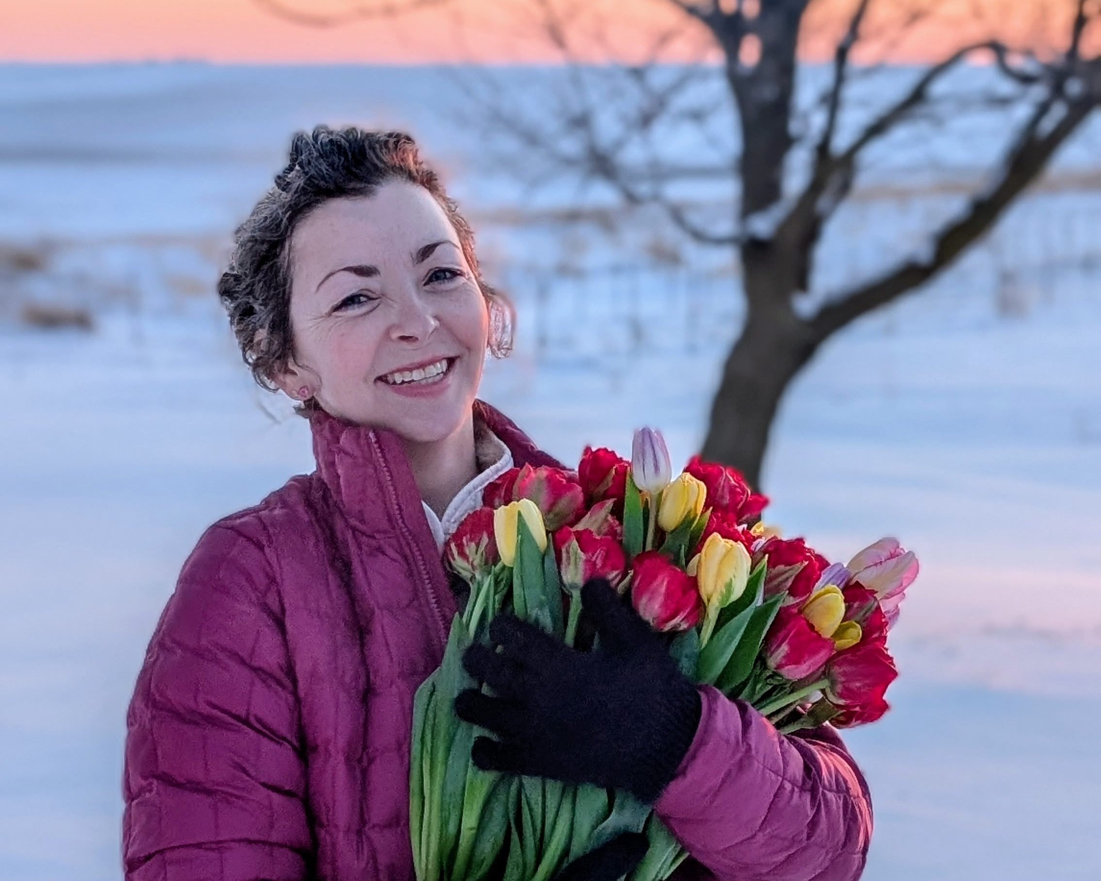 Woman holding a bouquet of tulips in a snowy landscape