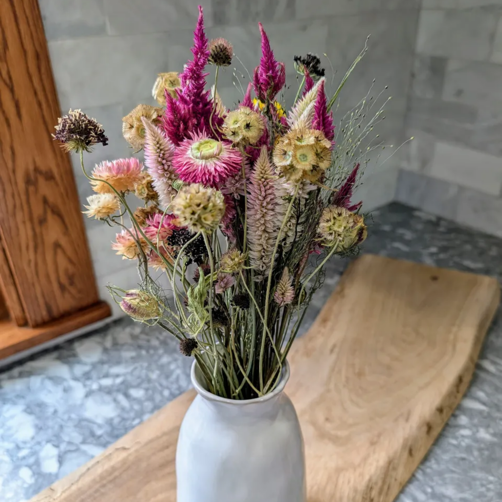 Decorative bouquet in a white vase on a wooden board with a marble floor background